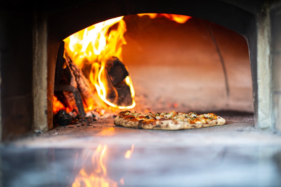 Wood fired pizza cooking in restaurant oven with flames